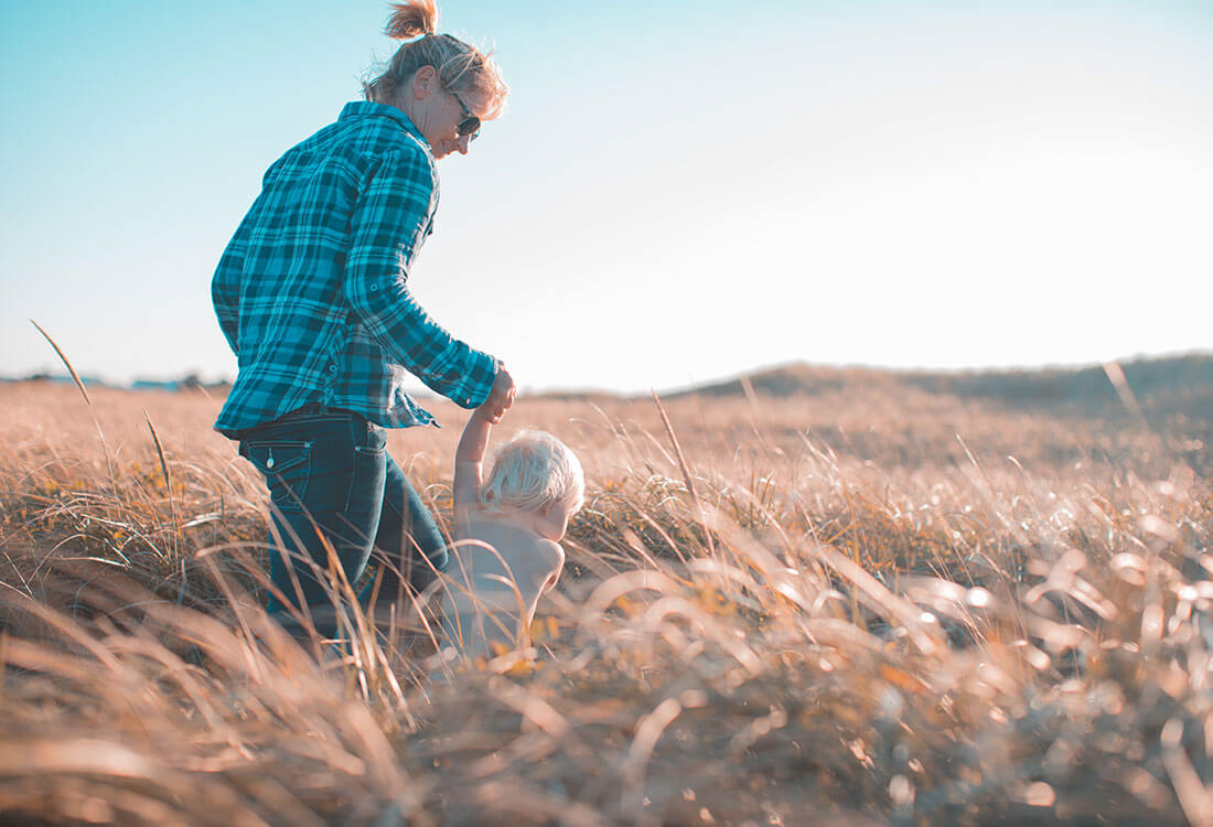Photo of a woman walking with a child in a field